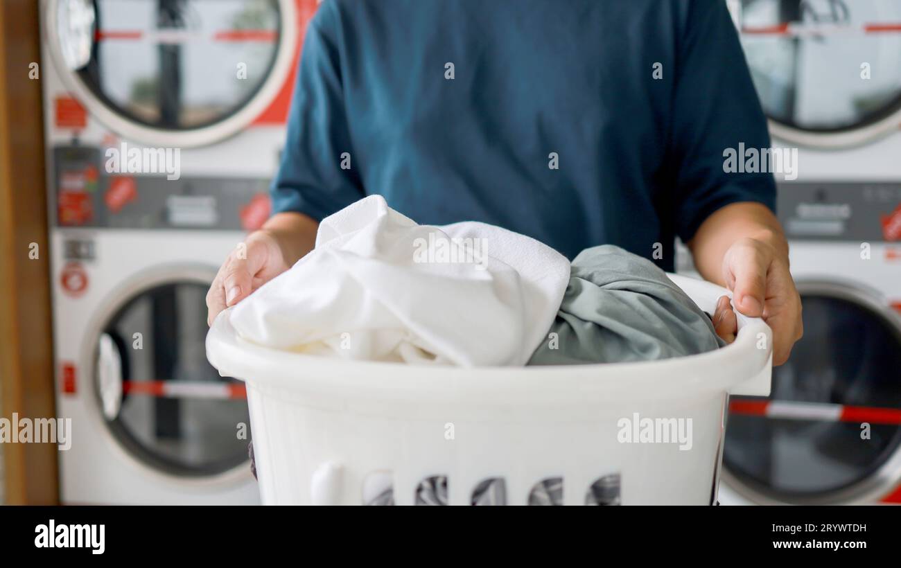 Man doing launder holding basket with dirty laundry of the washing machine in the public store. laundry clothes concept Stock Photo