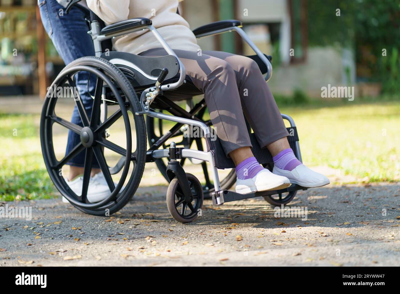 Nursing home. Young caregiver helping senior woman in wheelchair Stock