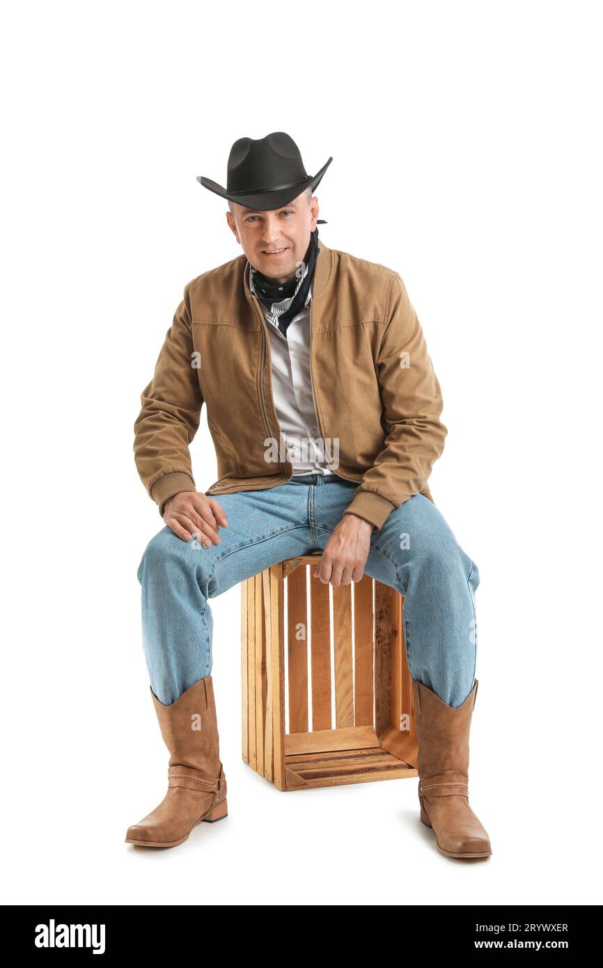 Mature cowboy sitting on white background Stock Photo