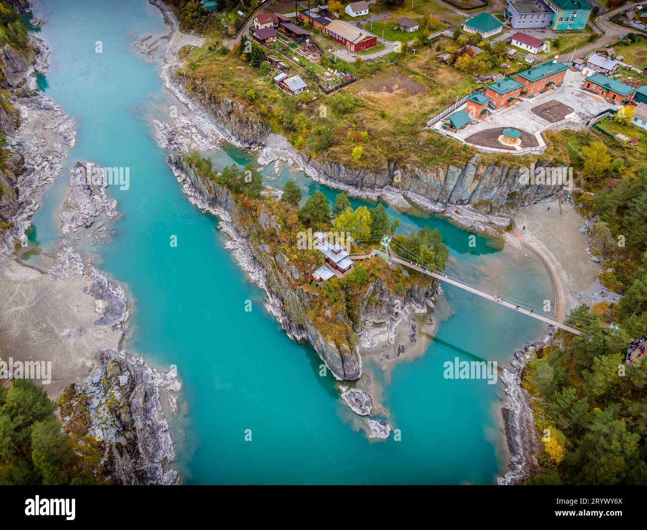 The aerial photo of Patmos orthodox church on the small island with the bridge across scenic Katun river in the Altai mountains in Russia. Stock Photo