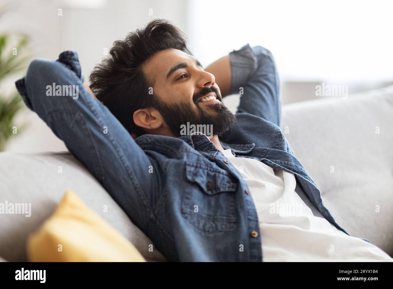 Relax Concept. Handsome Smiling Indian Man Leaning Back On Sofa At Home Stock Photo