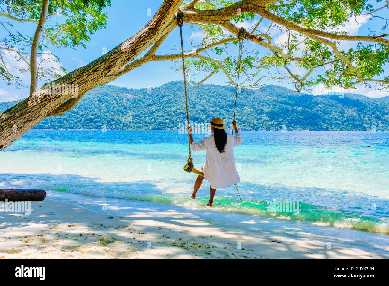 Woman at a rope swing on the beach of Koh Lipe Island Southern Thailand
