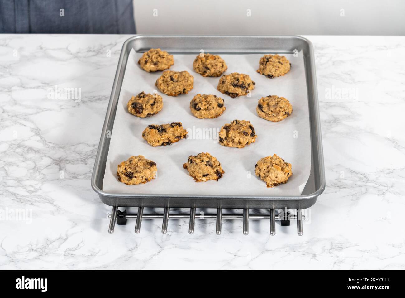 Scooping cookie dough with dough scoop into a baking sheet lined with  parchment paper to bake soft oatmeal raisin walnut cookies Stock Photo -  Alamy