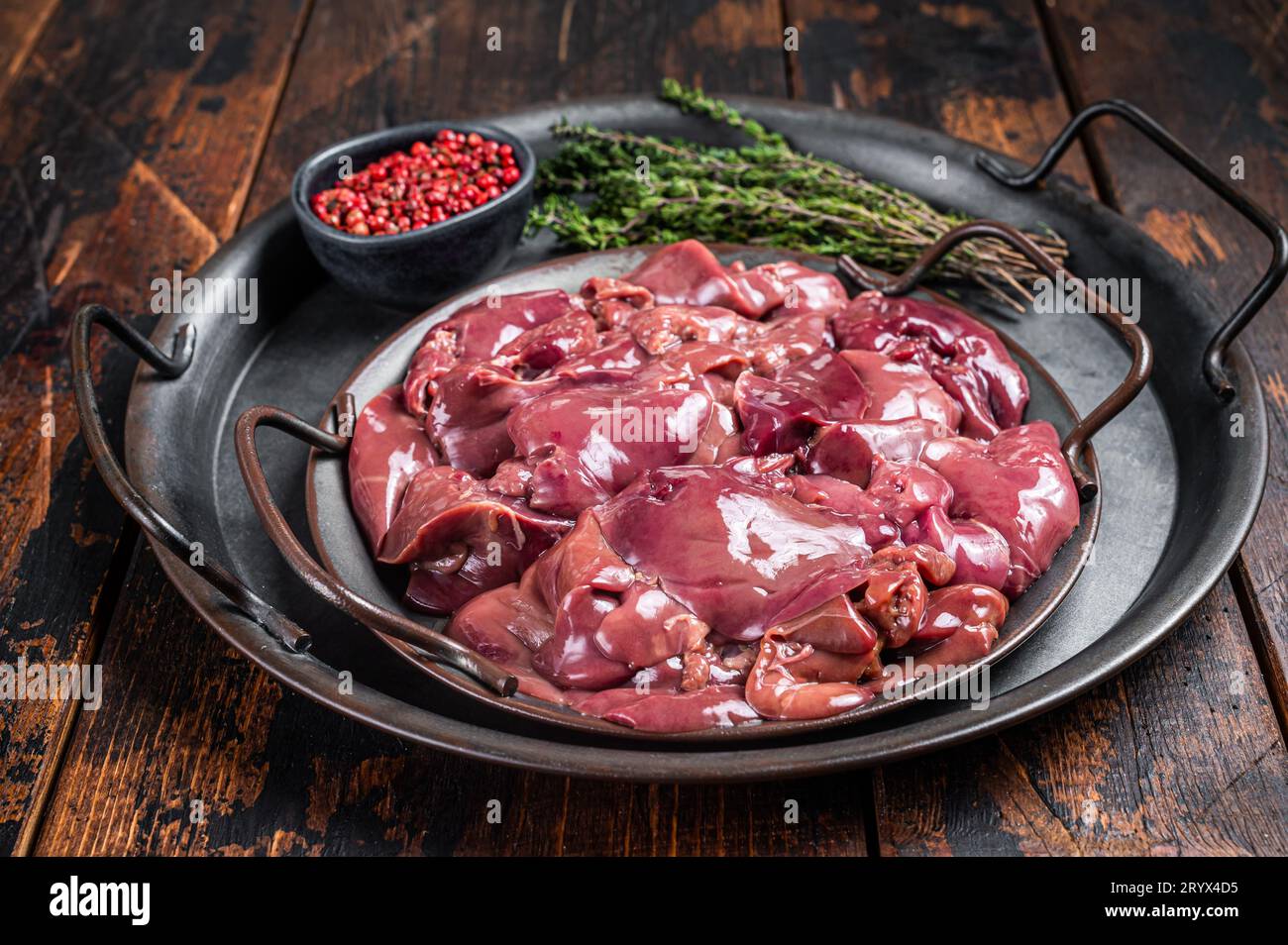 Fresh Raw chicken liver, poultry giblets in steel tray with herbs. Wooden background. Top view. Stock Photo