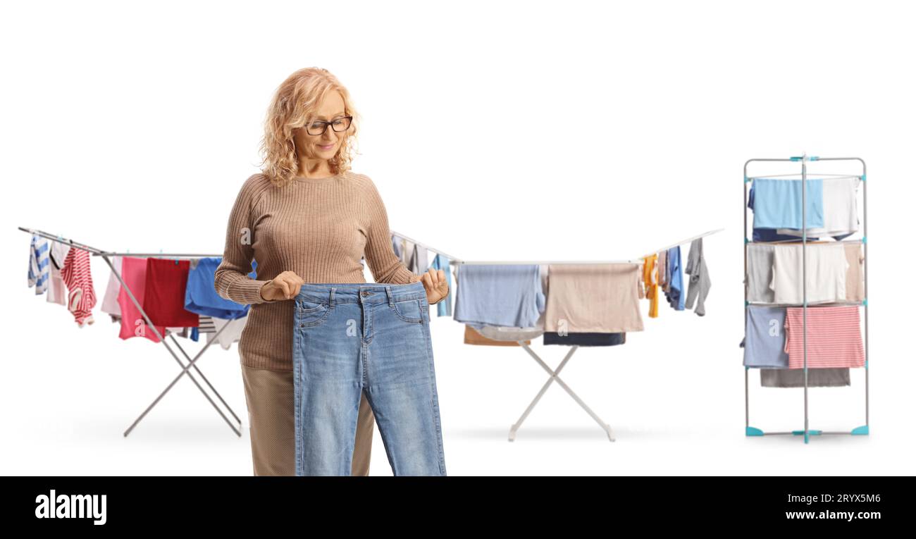 Woman holding a pair of jeans in front of clothes on racks isolated on white background Stock Photo