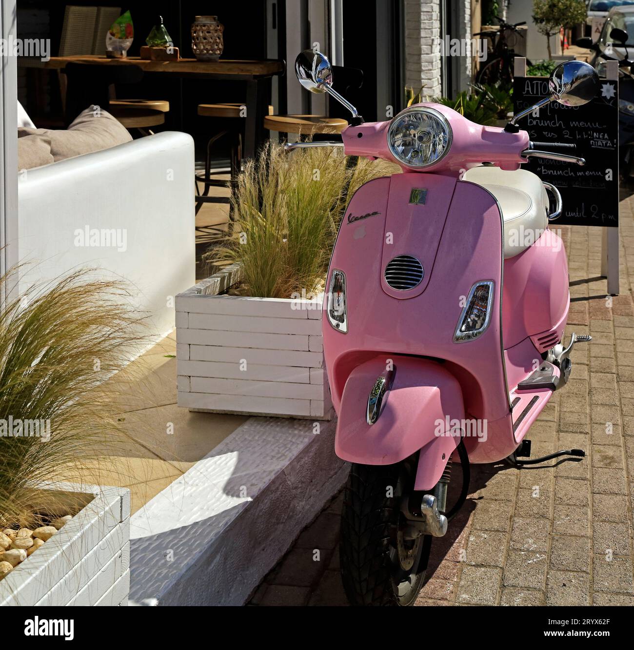 Pink Vespa motor scooter parked by the roadside, Agistri island, Saronic island group, Greece. Taken May 2023 Stock Photo