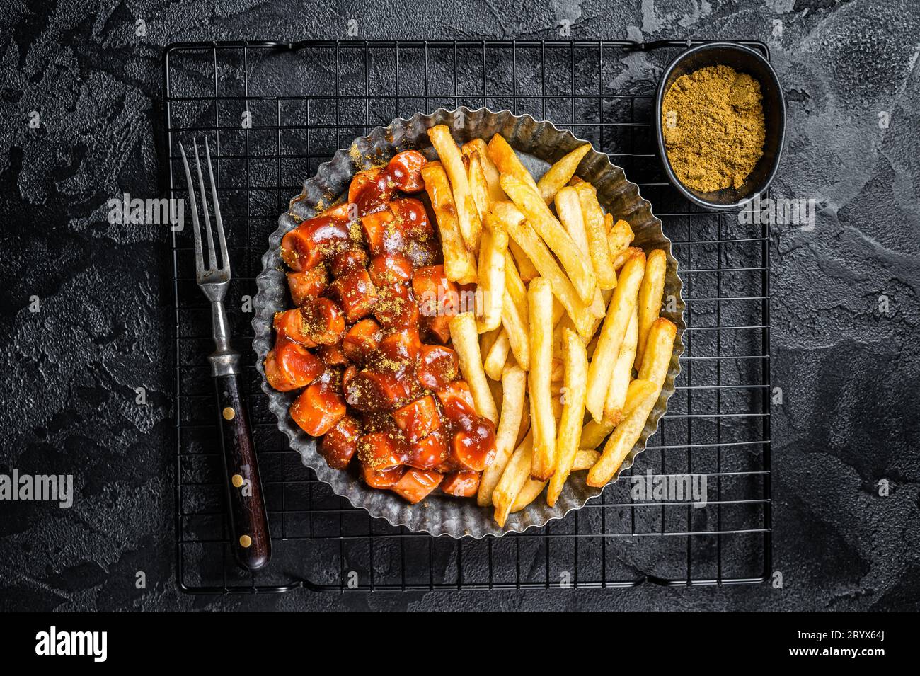 German fastfood currywurst meal, curry wurst with french fry. Black background. Top view. Stock Photo