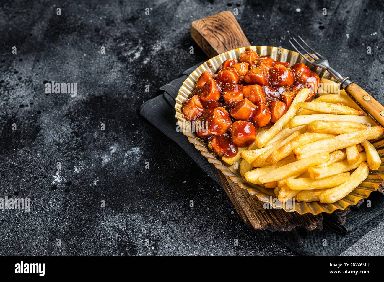 German currywurst with french fry served in a steel plate. Black background. Top view. Copy space. Stock Photo