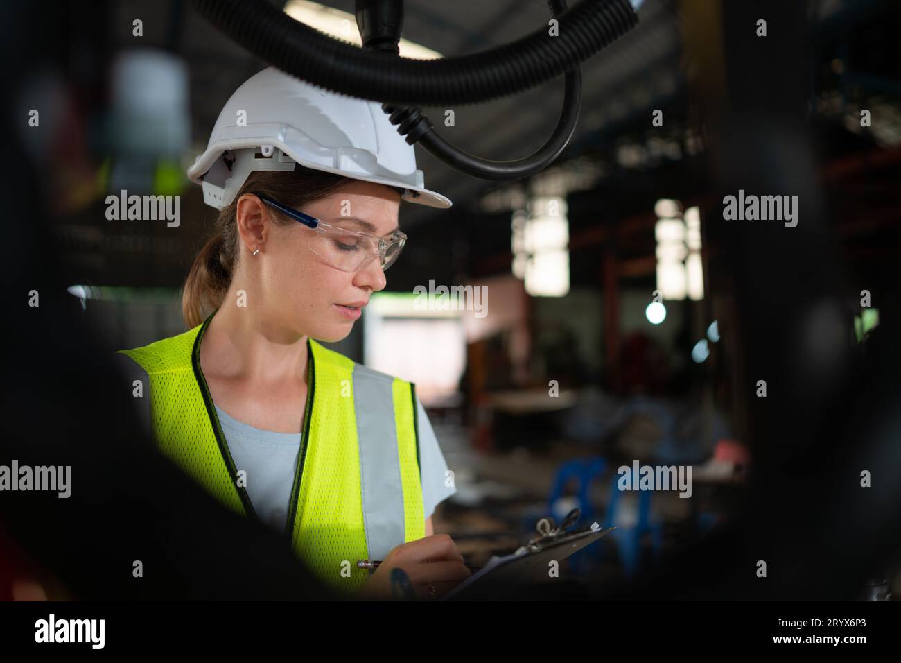Female electrical engineer with the mission of installing a robot arm electrical system Stock Photo