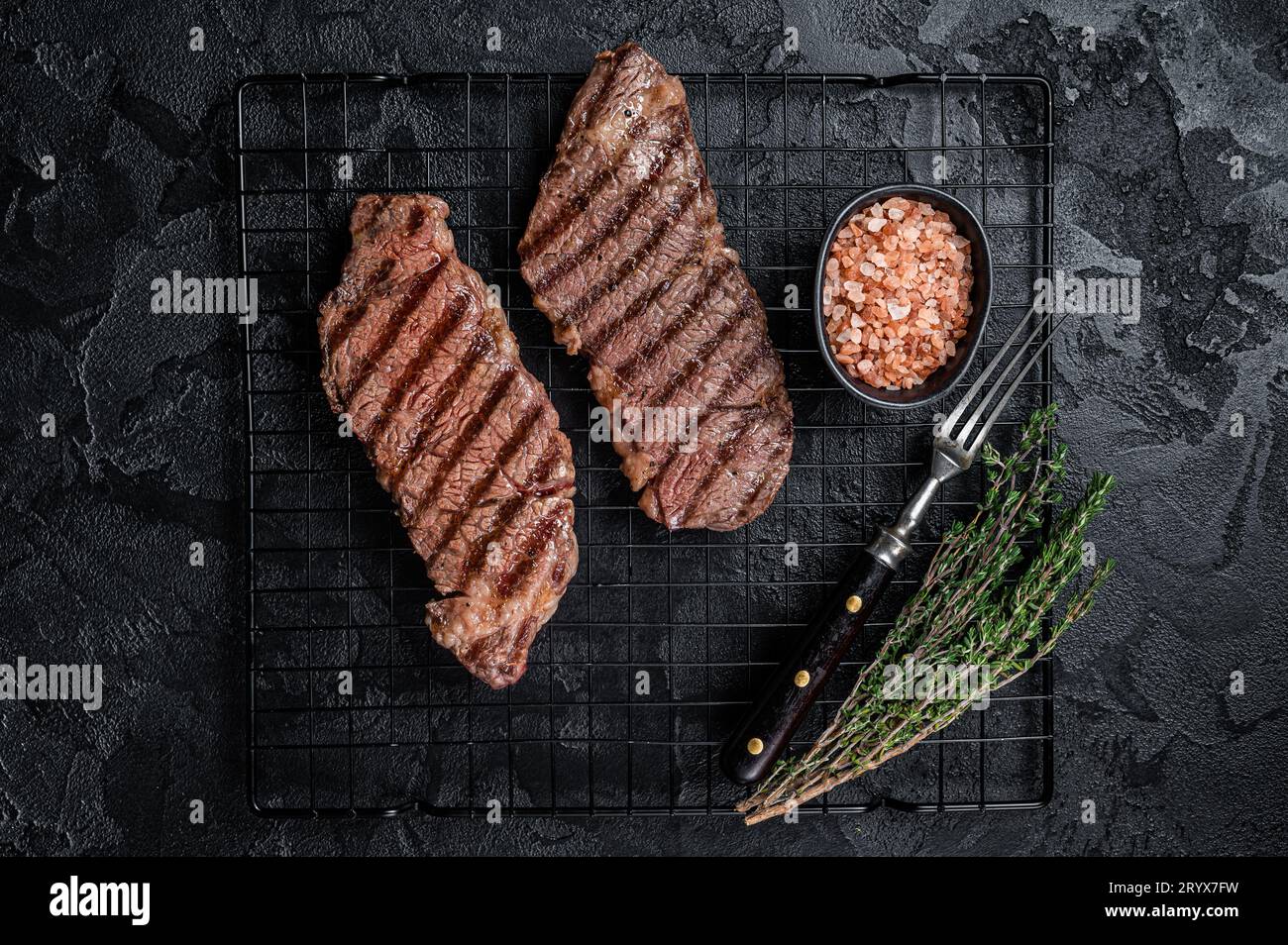 Grilled denver beef meat steak on a rack. Black background. Top view. Stock Photo