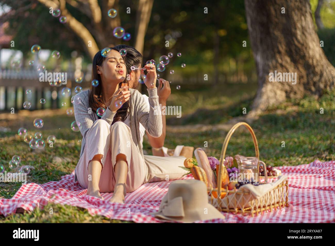 In love couple enjoying picnic time blow soap bubbles in park outdoors Picnic. happy couple relaxing togetherÂ with picnic Baske Stock Photo
