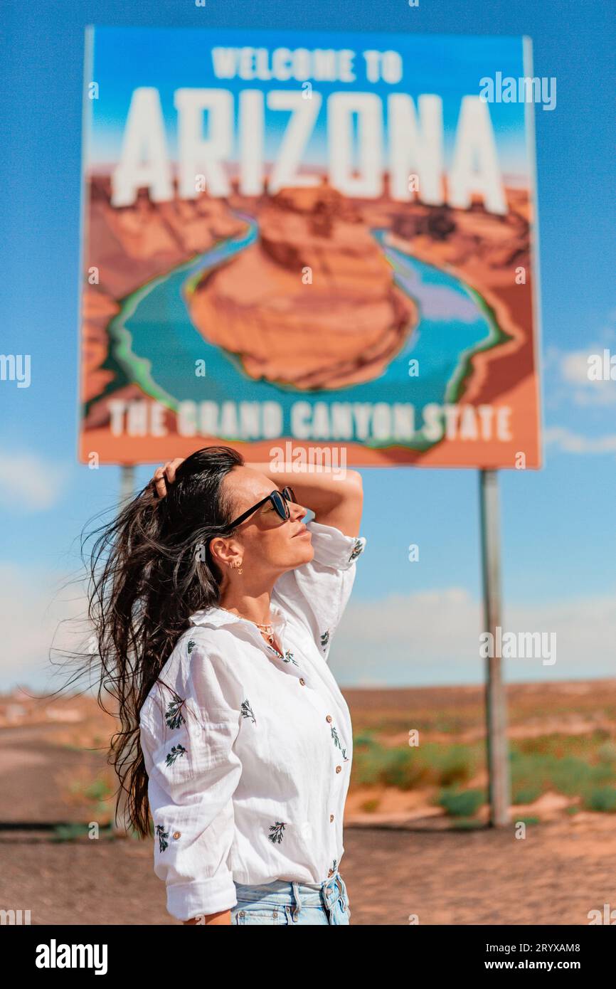 Beautiful woman on her trip to the USA on the background of Welcome to Arizona State border sign right in the Paje Canyon, USA Stock Photo