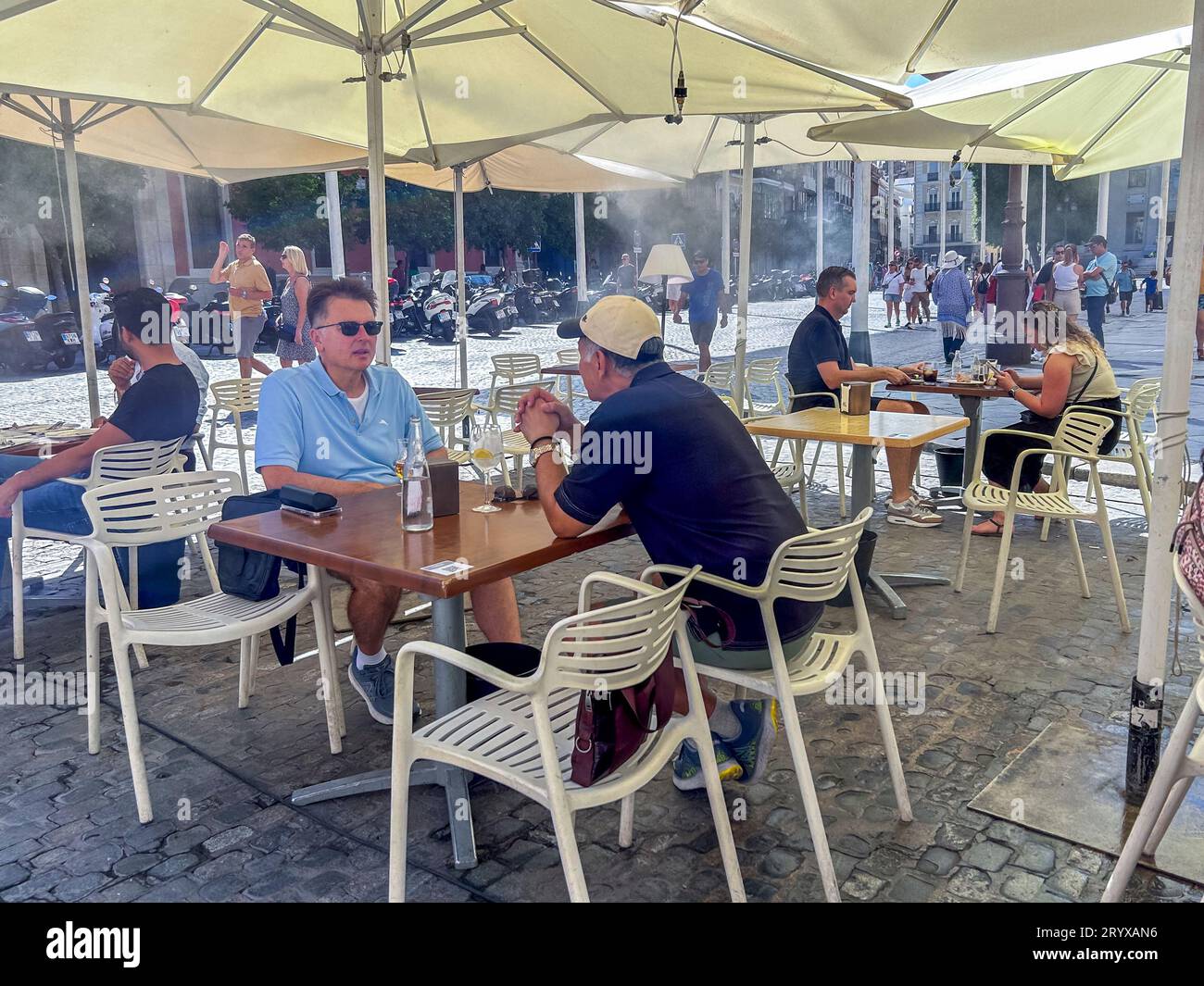 Seville, Spain, Small Group People, Men,  Sharing Drinks on Cafe Terrace with Water mist to Cool, on Hot Day, on Street Scene, in Old Town Center, neighborhoods Stock Photo