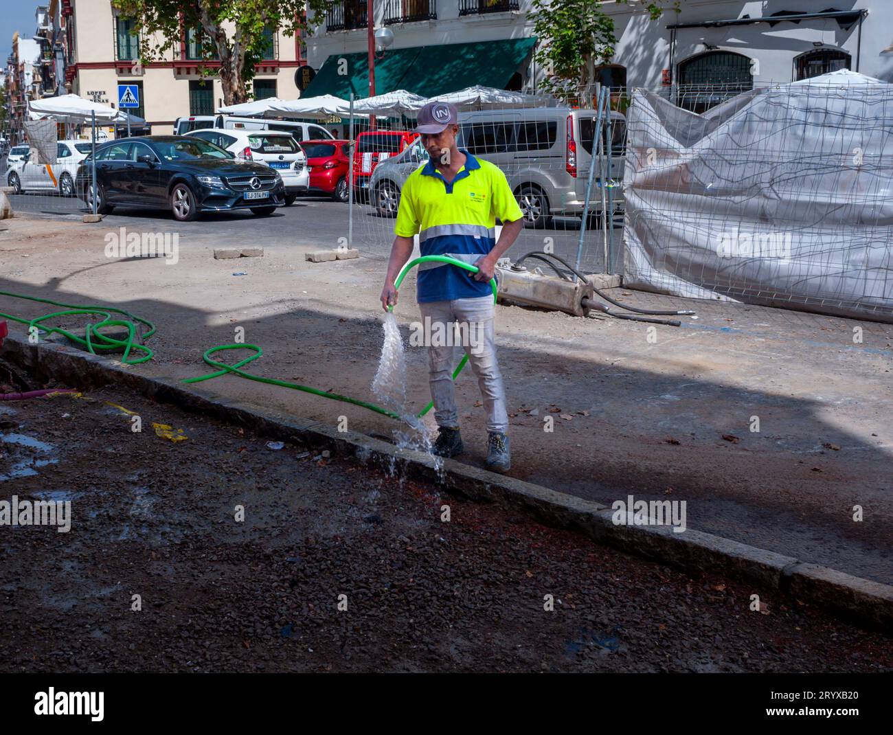 Seville Spain, Construction WOrkers on Street, in Old Town Center, Heat Wave, Watering Down Pavement Stock Photo