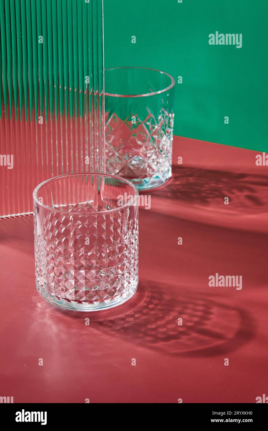 Two empty glass glasses on colored backgrounds with shadows from sunlight Stock Photo