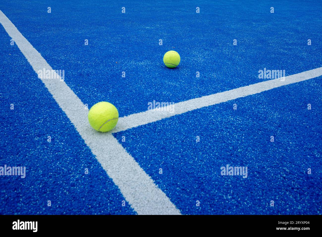 two paddle tennis balls over the line of a blue paddle tennis court Stock Photo