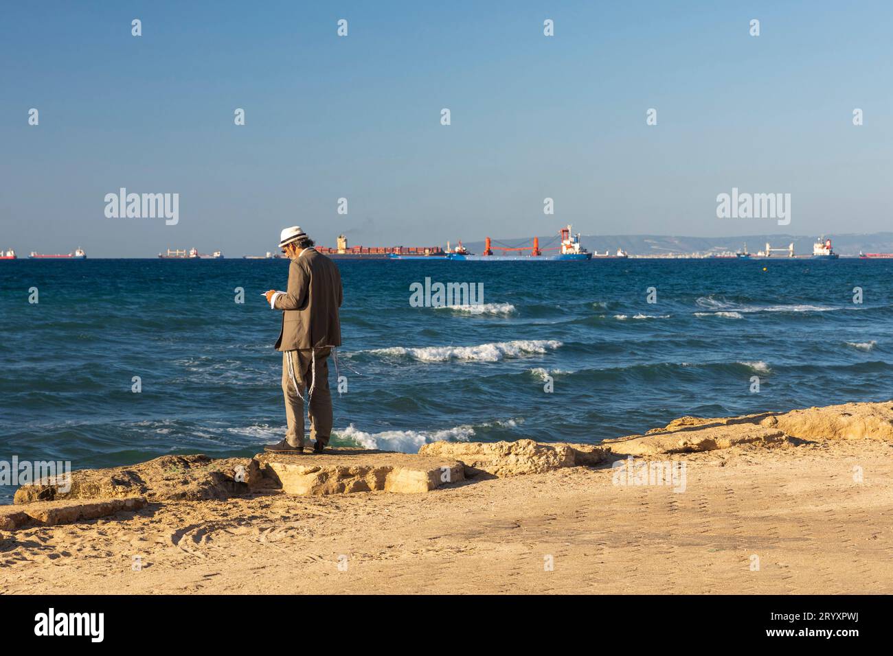 Haifa, Israel - September 27, 2023, An Orthodox man wearing a knitted kippah reads a prayer on the Jewish New Year Rosh Hashanah on the shores of the Stock Photo
