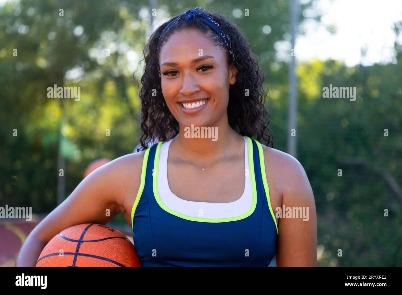 Portrait of happy biracial female basketball player holding basketball