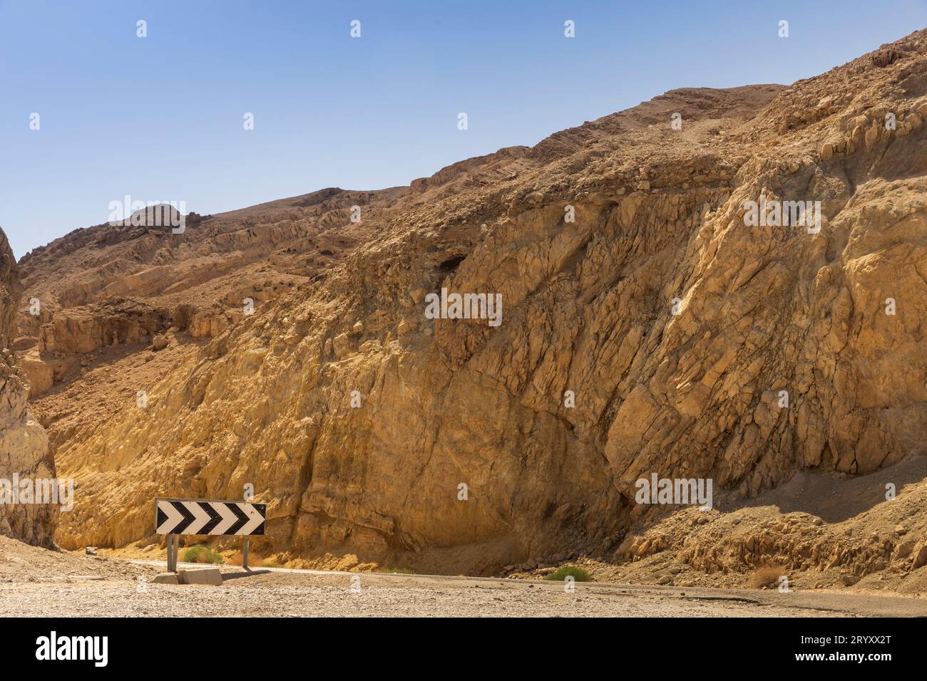 A highway with a rocky mountain on the side, power poles and sky in the background, desert Dead Sea, Israel Stock Photo