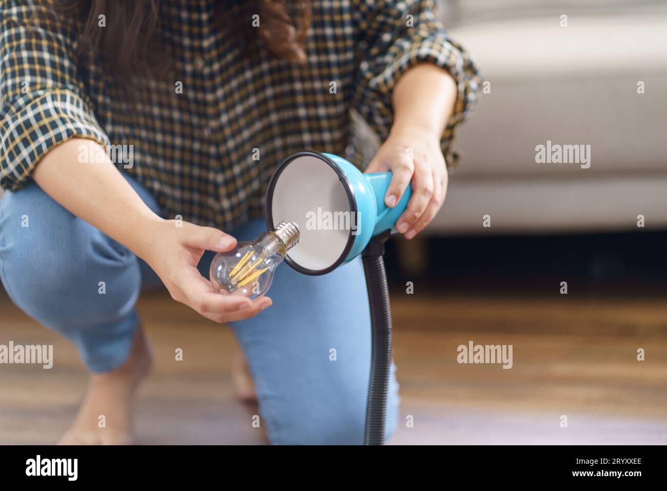 Asian Woman changing light bulb in lamp renovation using equipment to diy repairing light bulb and lamp sitting on the floor at Stock Photo