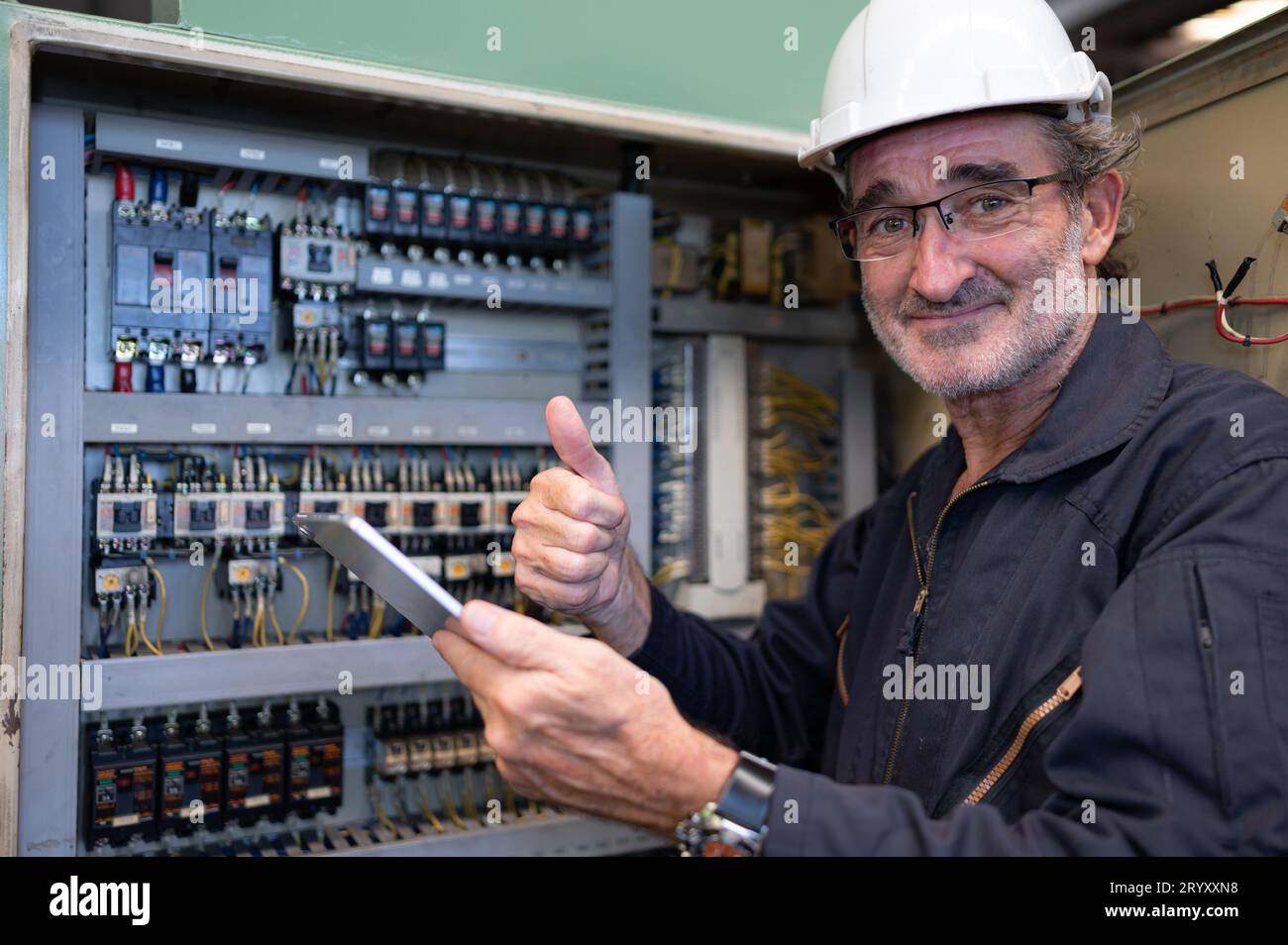 Senior engineer inspects the electrical system and repairs the mechanical system in the machine control cabinet. in order for th Stock Photo