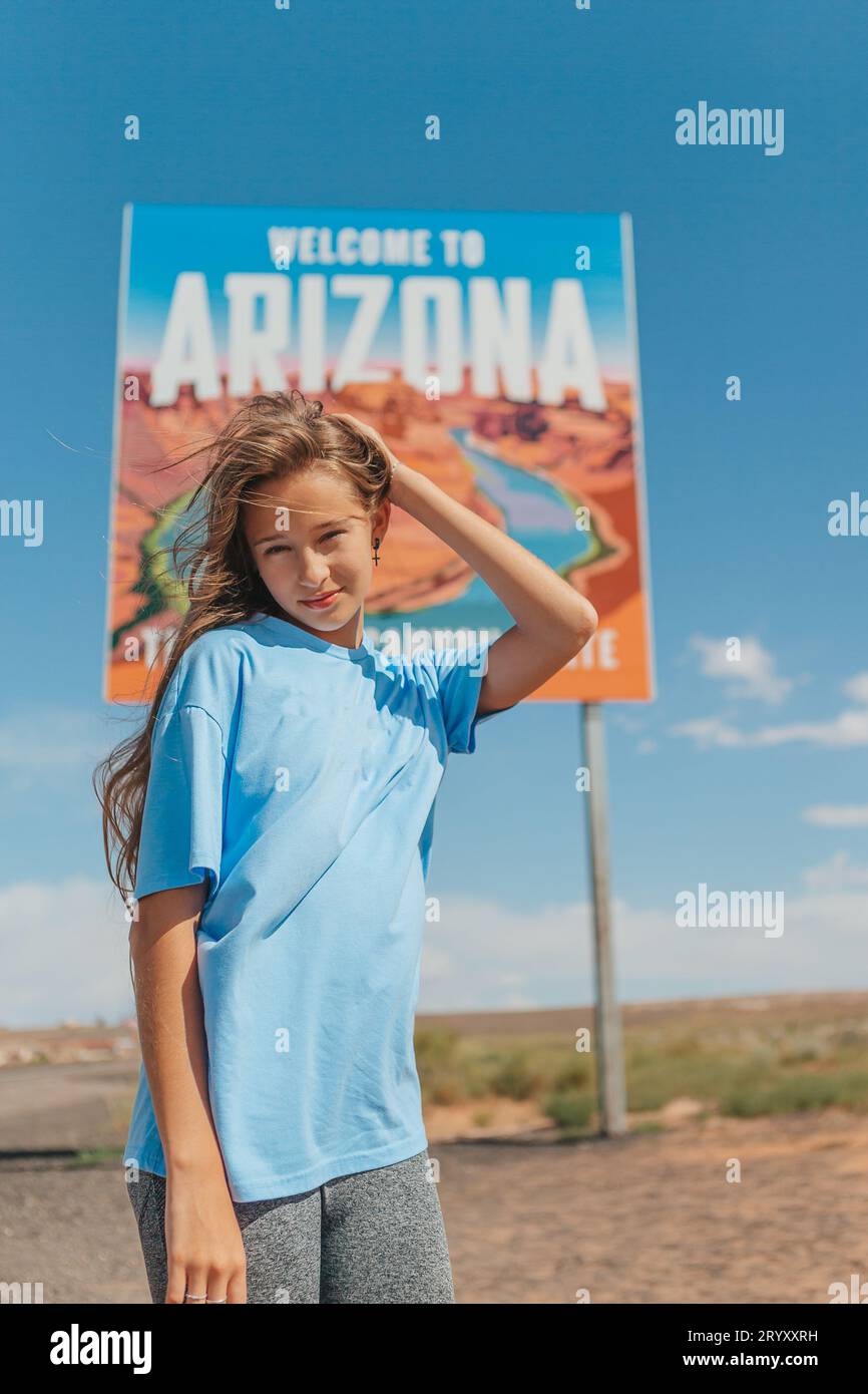 Beautiful woman on her trip to the USA on the background of Welcome to Arizona State border sign right in the Paje Canyon, USA Stock Photo