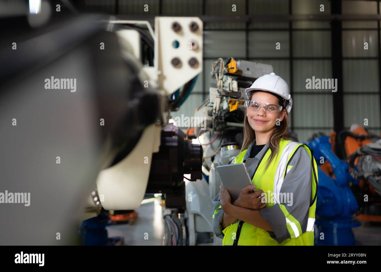 In the robots warehouse, Female engineer happily with updating software and calibrating a robotics arm. Stock Photo