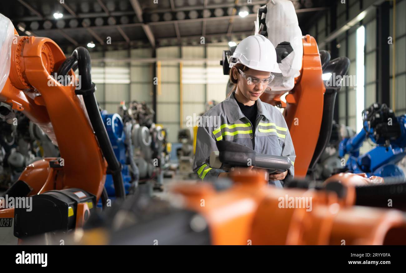 After installing a program on the robotic arm, a female engineer with a robotic arm controller performs a test run. Stock Photo