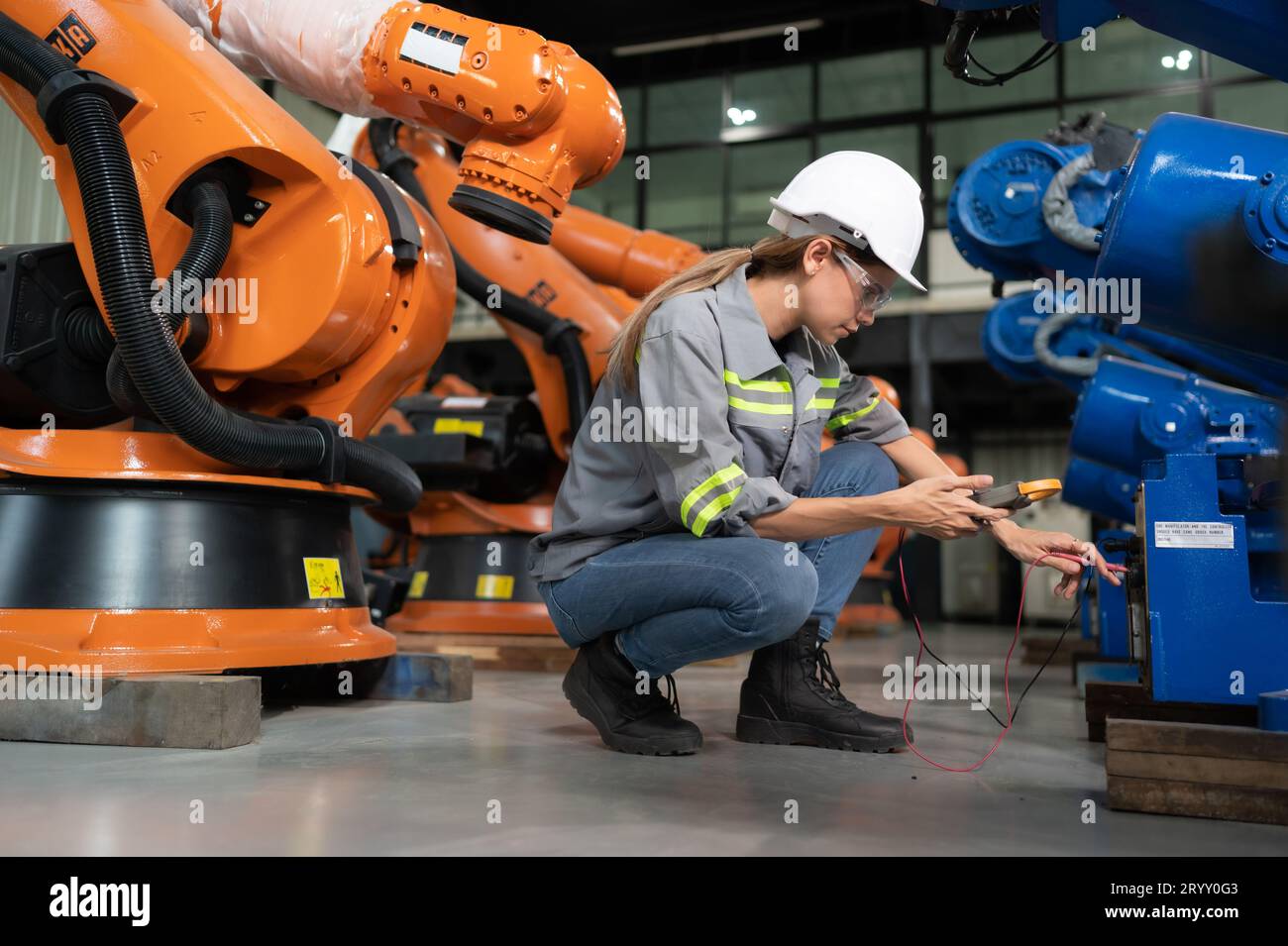 In the robots warehouse, A female engineer inspects the electrical system of every robotics arm, before delivering to the custom Stock Photo