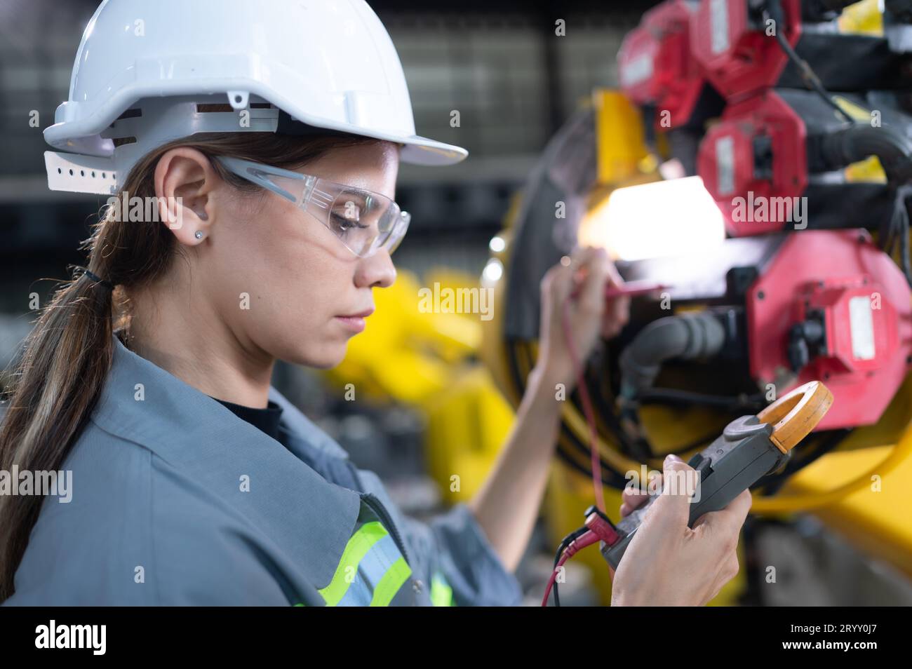In the robots warehouse, A female engineer inspects the electrical system of every robotics arm, before delivering to the custom Stock Photo