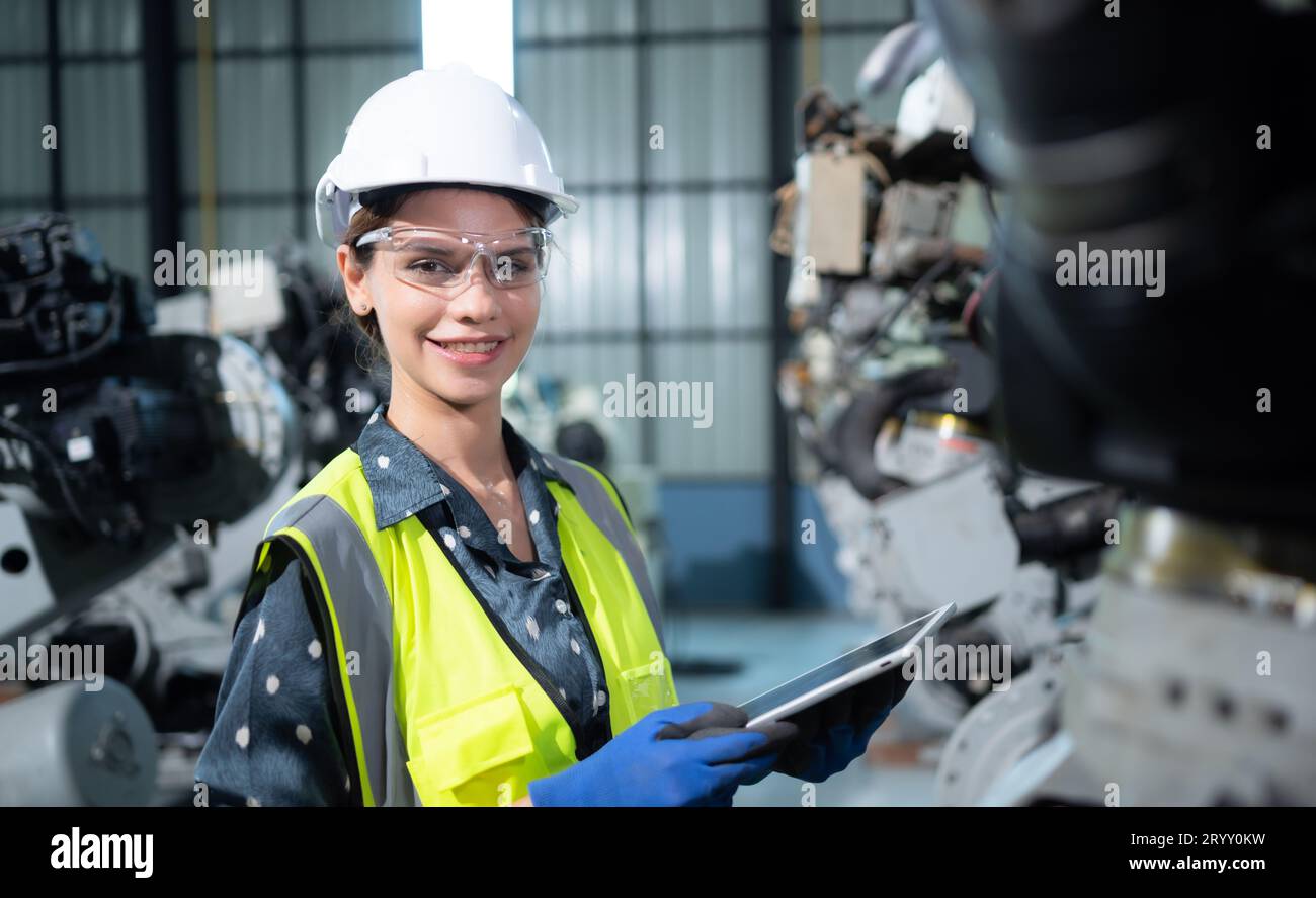 A female engineer installs a program on a robotics arm in a robot warehouse. And test the operation before sending the machine t Stock Photo