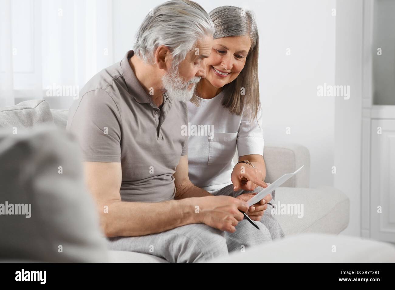 Senior couple solving crossword on sofa at home Stock Photo