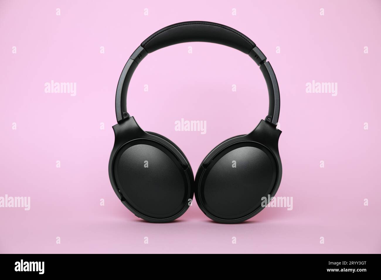 Modern black wireless headphones on pink background Stock Photo