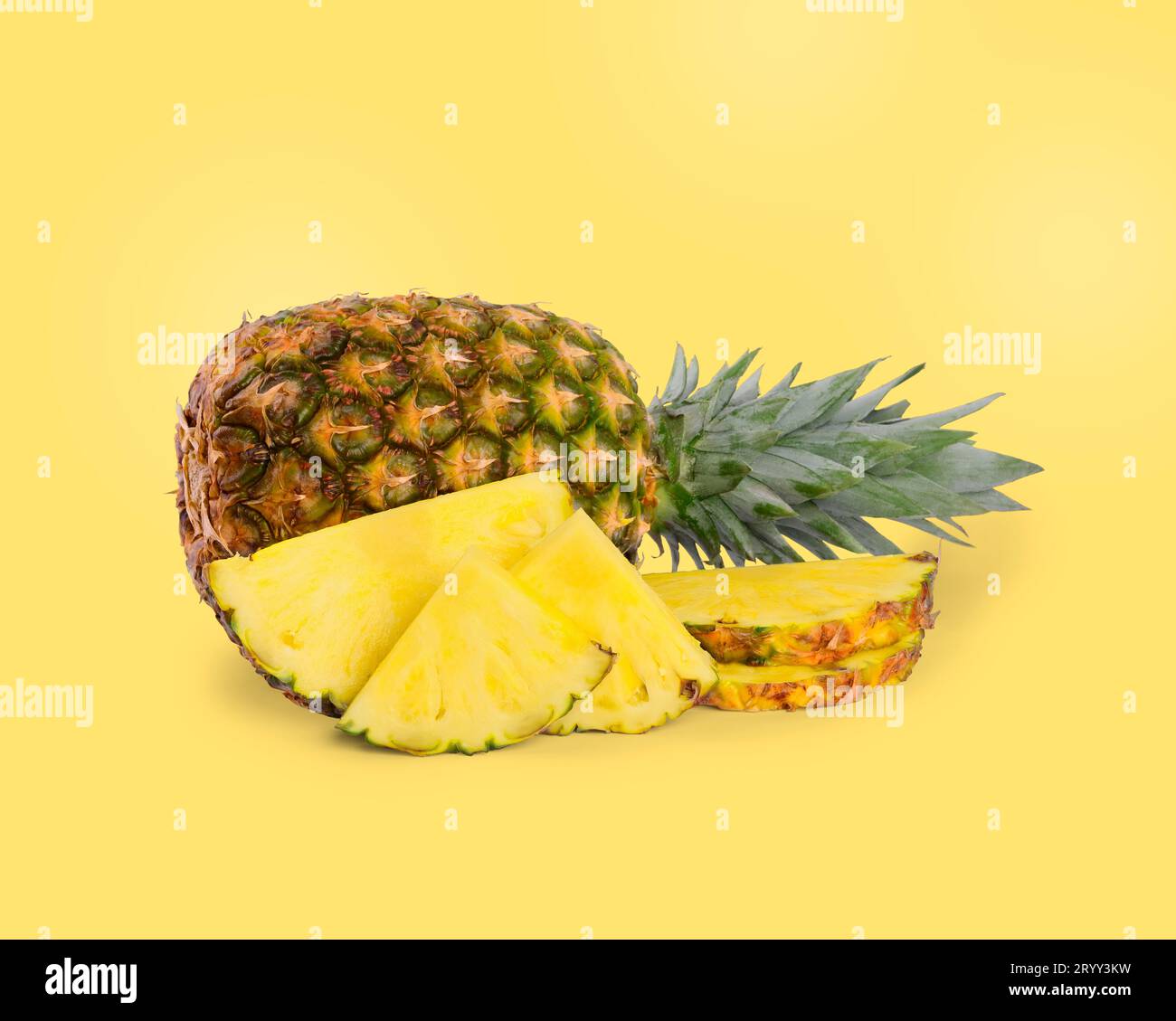 Cut and whole pineapples on light yellow background Stock Photo