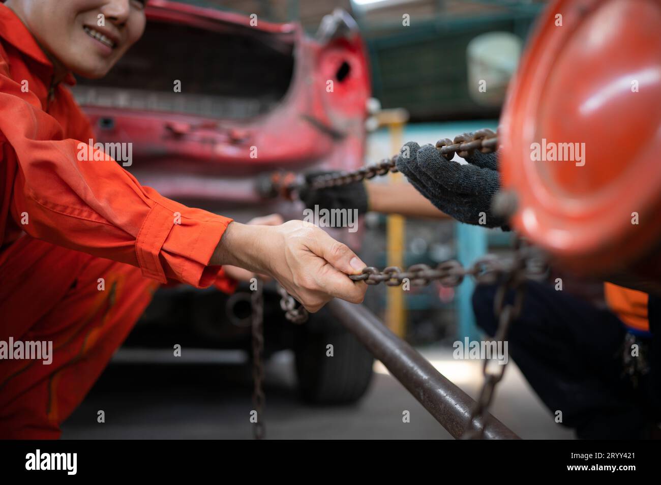 To return the automobile body to its former shape, an auto repair mechanic uses a machine to pull the car body caused by a heavy Stock Photo