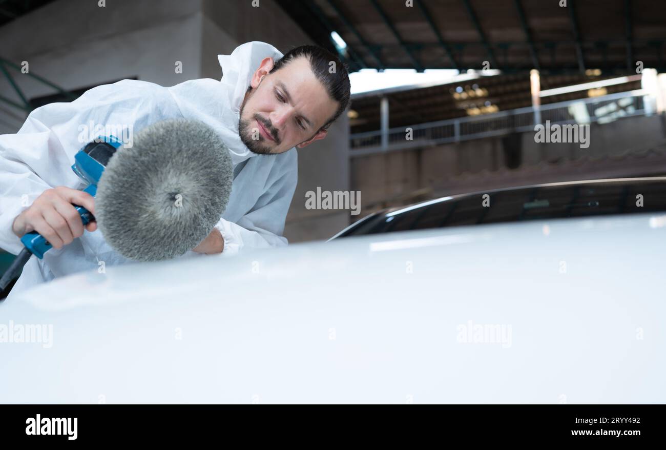 Auto mechanic use an electric polisher to polish the dried car paint