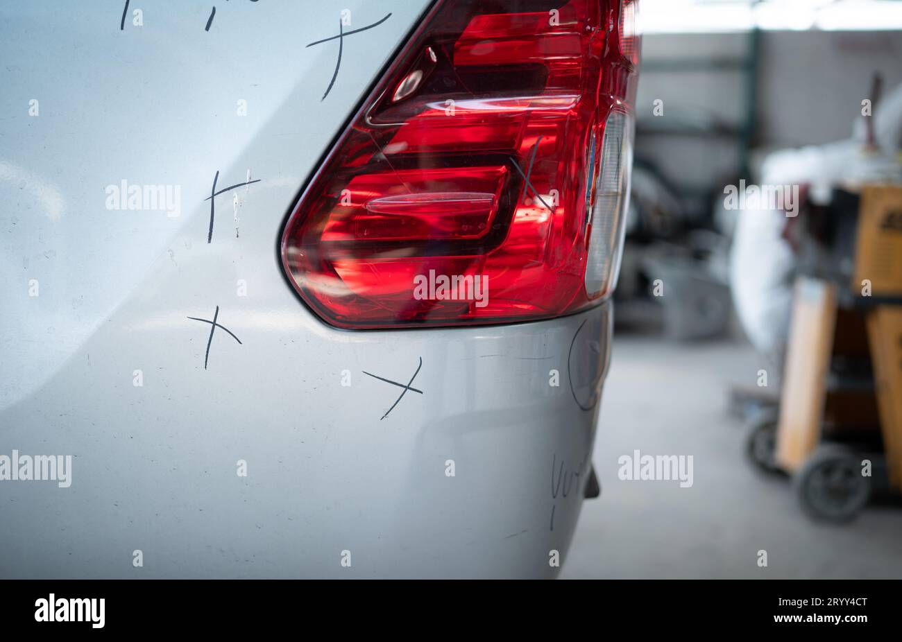 A car mechanic checks the condition of a car body to be repaired after a collision. by marking the X that need to be repaired Stock Photo