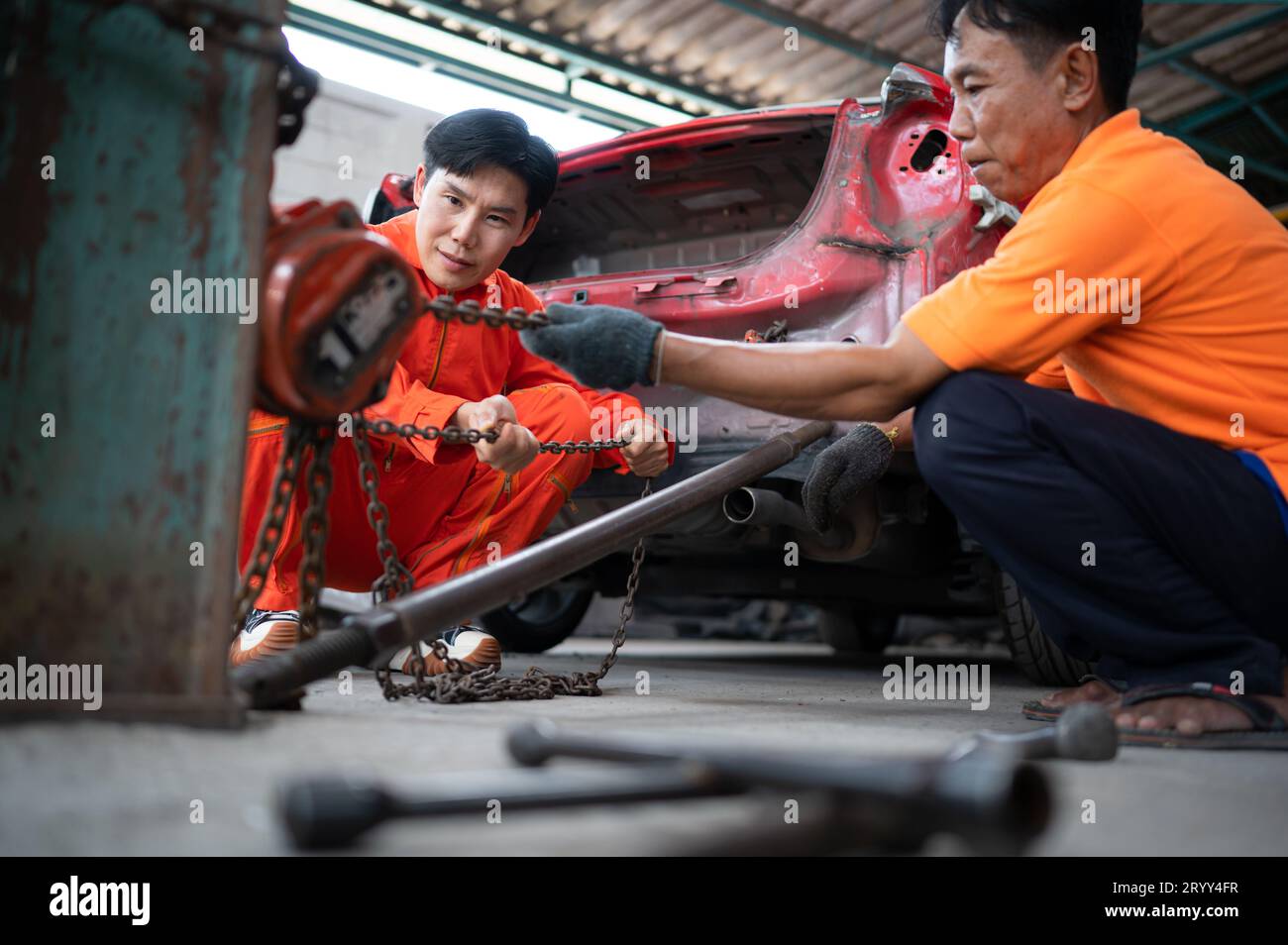 To return the automobile body to its former shape, an auto repair mechanic uses a machine to pull the car body caused by a heavy Stock Photo