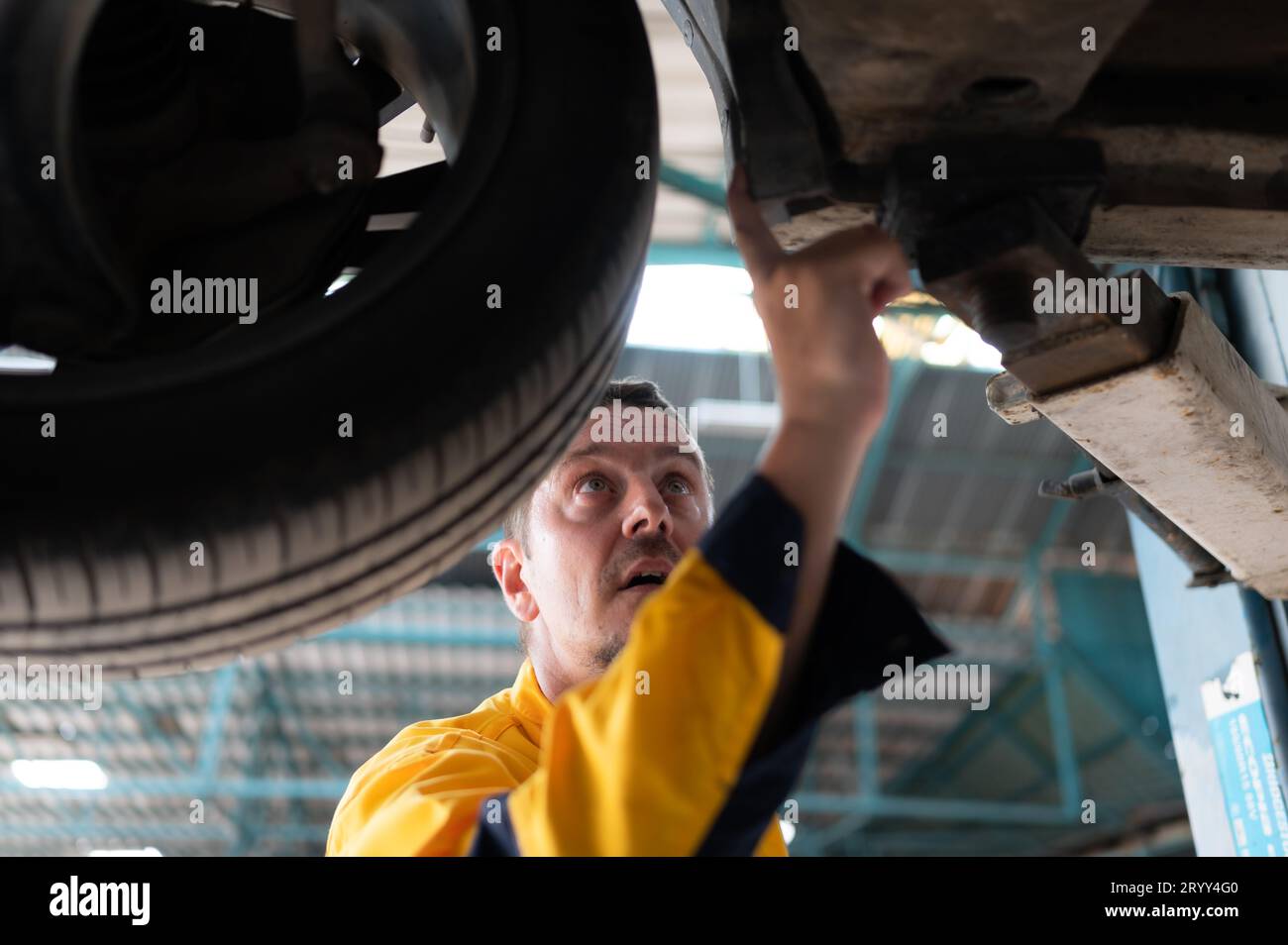Auto repair mechanic the undercarriage of the car is being inspected