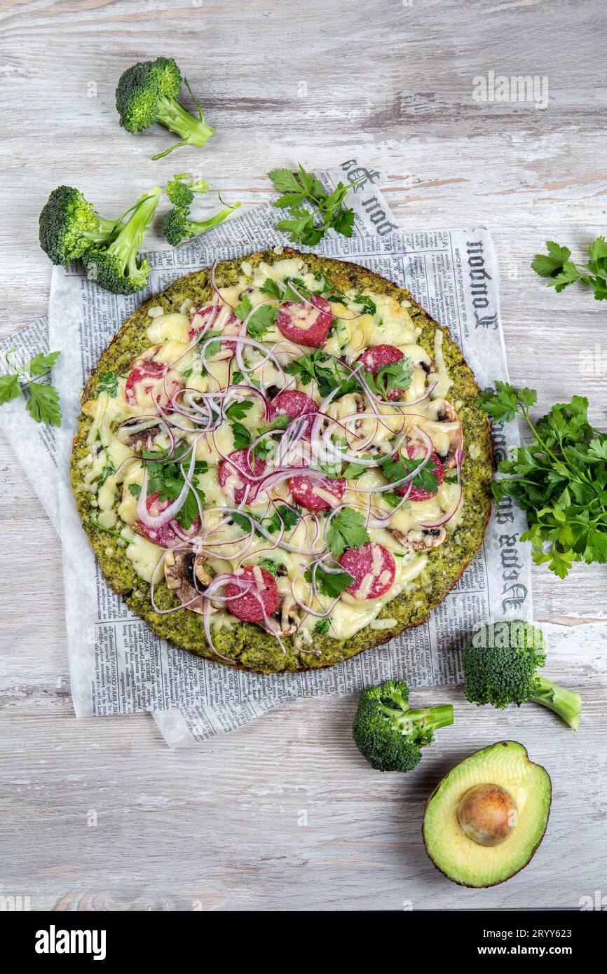 Crust Broccoli base low carbs keto pizza with salami, avocado on vintage newspapper. Top view Stock Photo