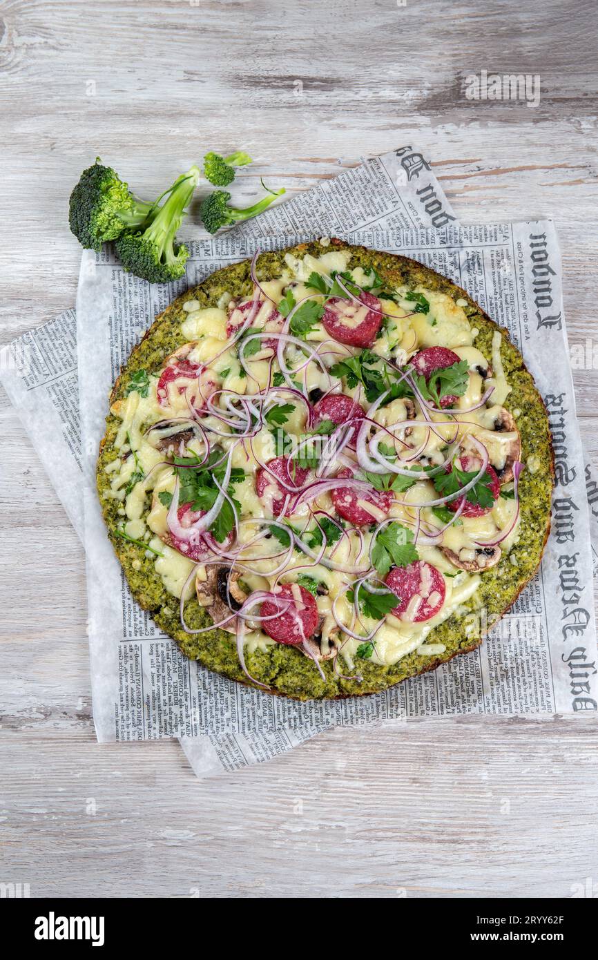 Crust Broccoli base low carbs keto pizza with salami, avocado on vintage newspapper. Top view Stock Photo