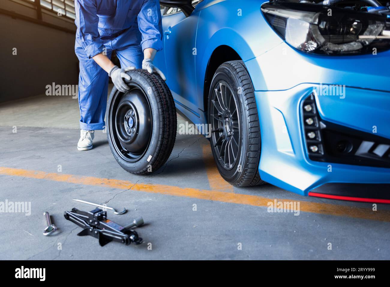 Car mechanics changing tire at auto repair shop garage. Transportation