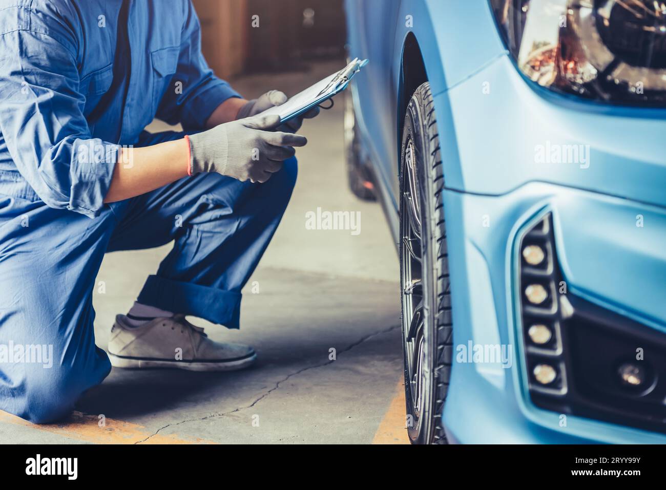 Asian car mechanic technician holding clipboard and checking to maintenance vehicle by customer claim order in auto repair shop Stock Photo