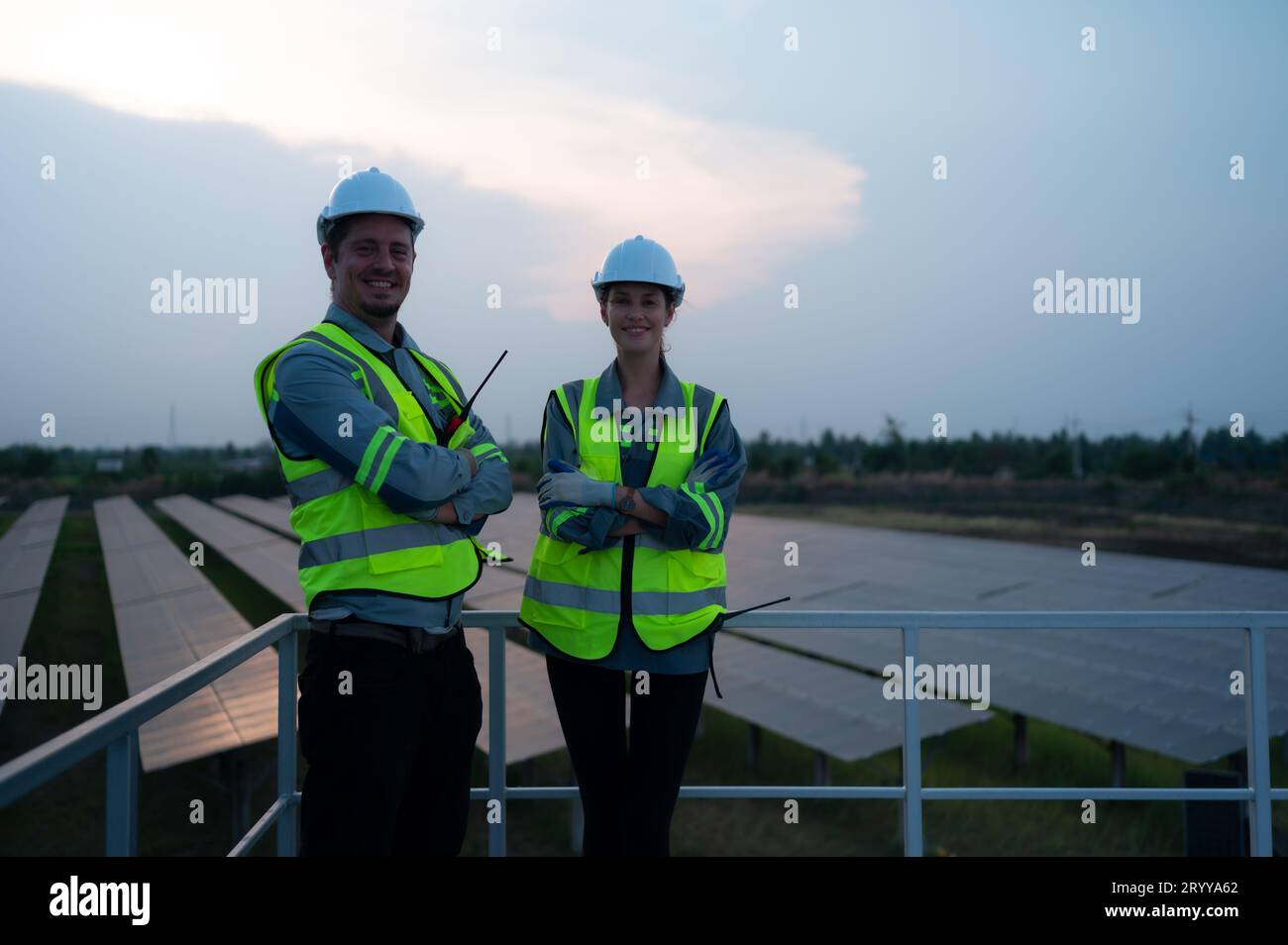 A team of electrical engineers inspecting solar panels in a hundred acres of grass on the rooftop of energy storage station, in Stock Photo