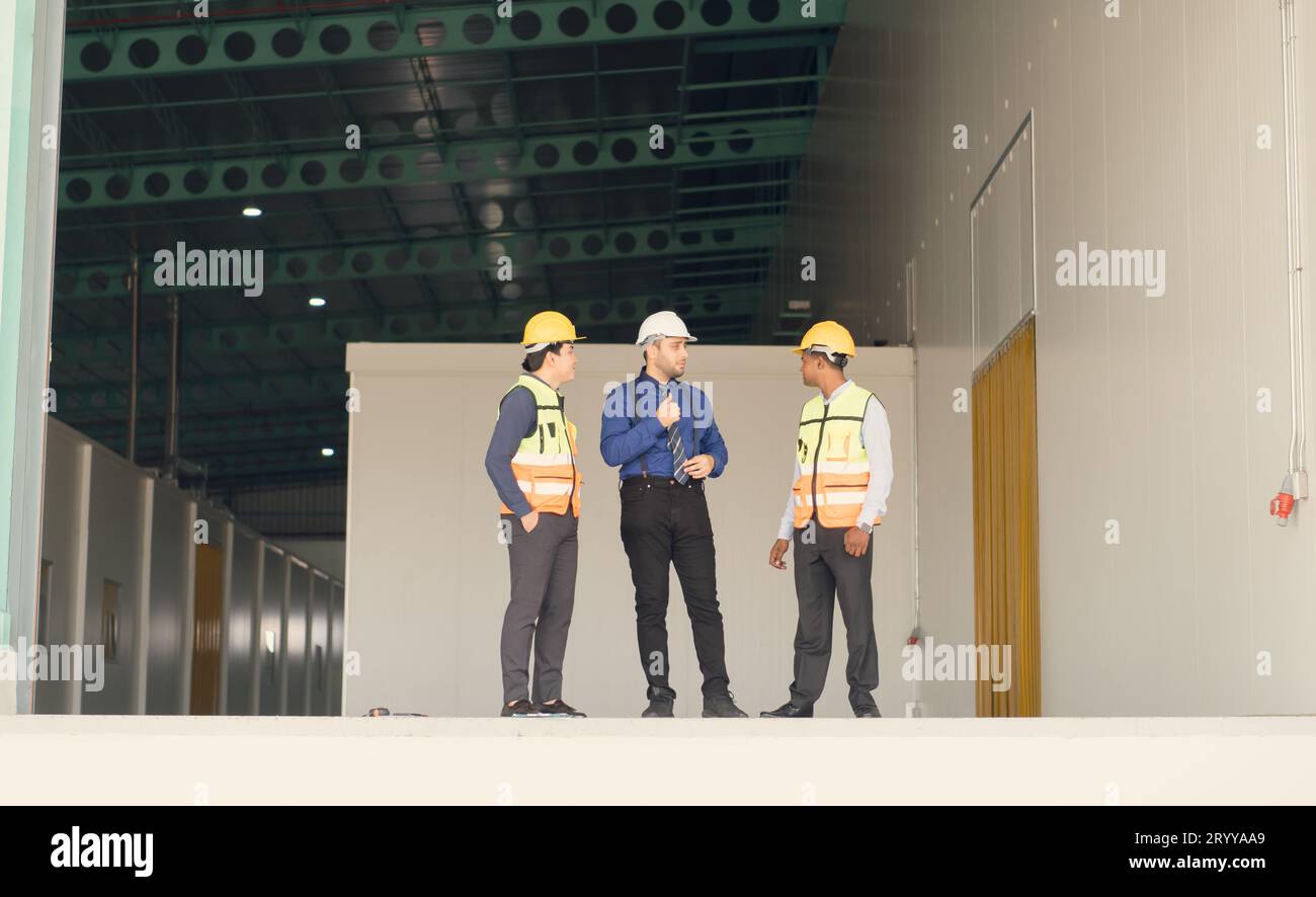 A warehouse manager and two employees are resting after dealing with how to organize the shelves in a large warehouse. Stock Photo