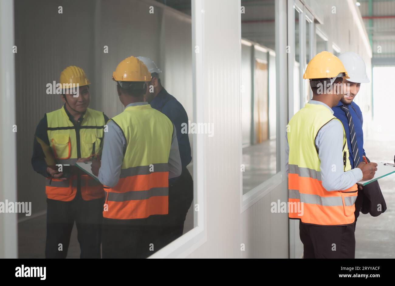 The warehouse manager advises the two employees on how to organize the shelves in a vast warehouse. Stock Photo