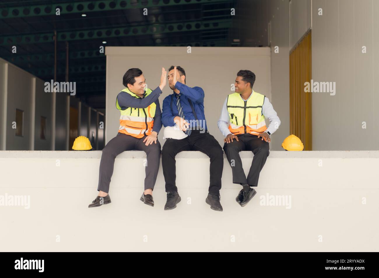 A warehouse manager and two employees are resting after dealing with how to organize the shelves in a large warehouse. Stock Photo