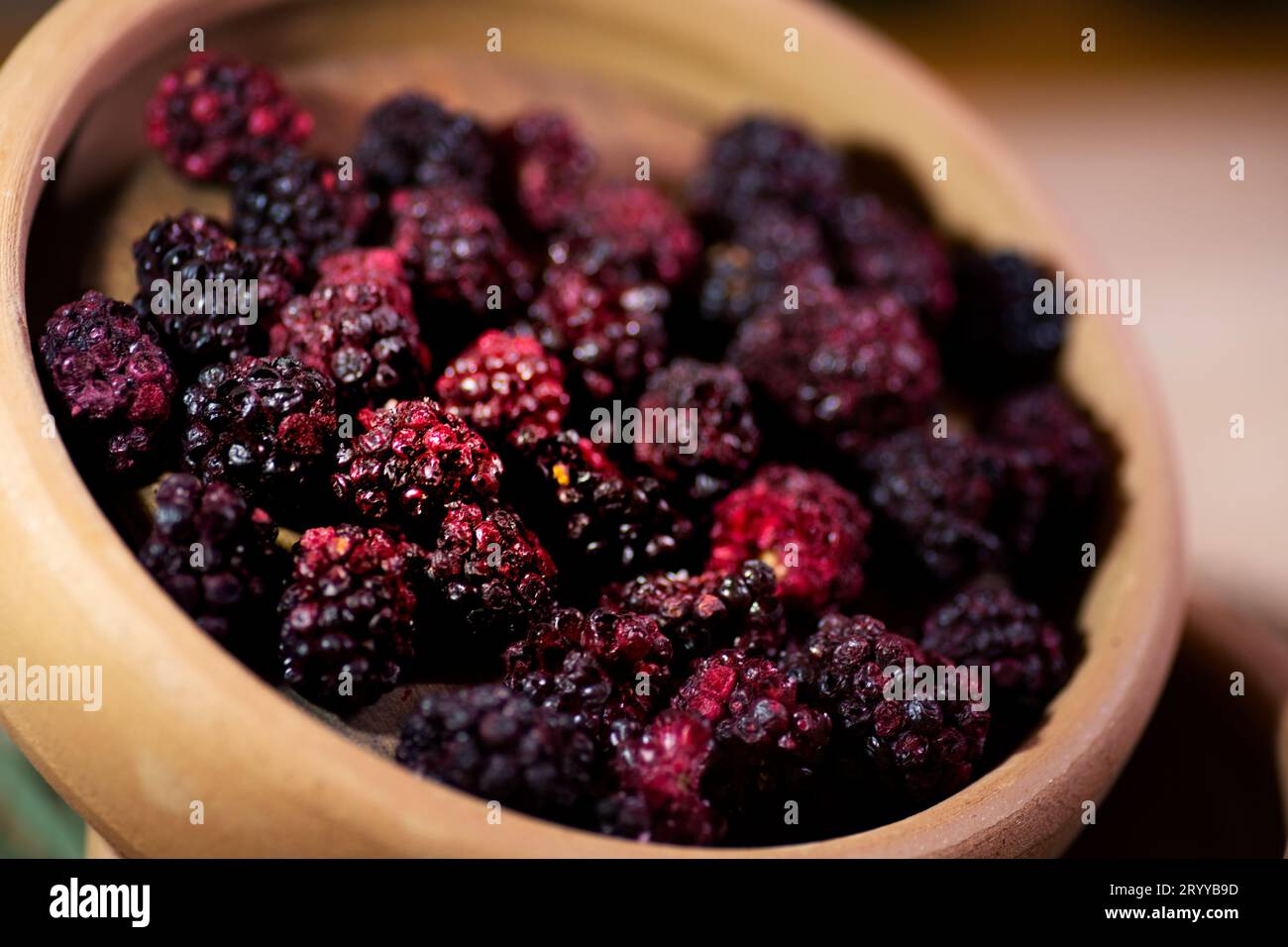 An up-close, detailed shot capturing a bowl brimming with fresh, red blackberries. The focus is sharp, highlighting the texture and rich color of the Stock Photo