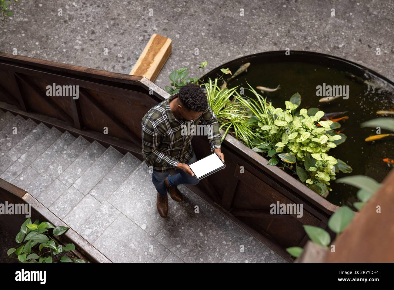 Overhead view of african american man holding a digital tablet with copy space on stairs at office Stock Photo