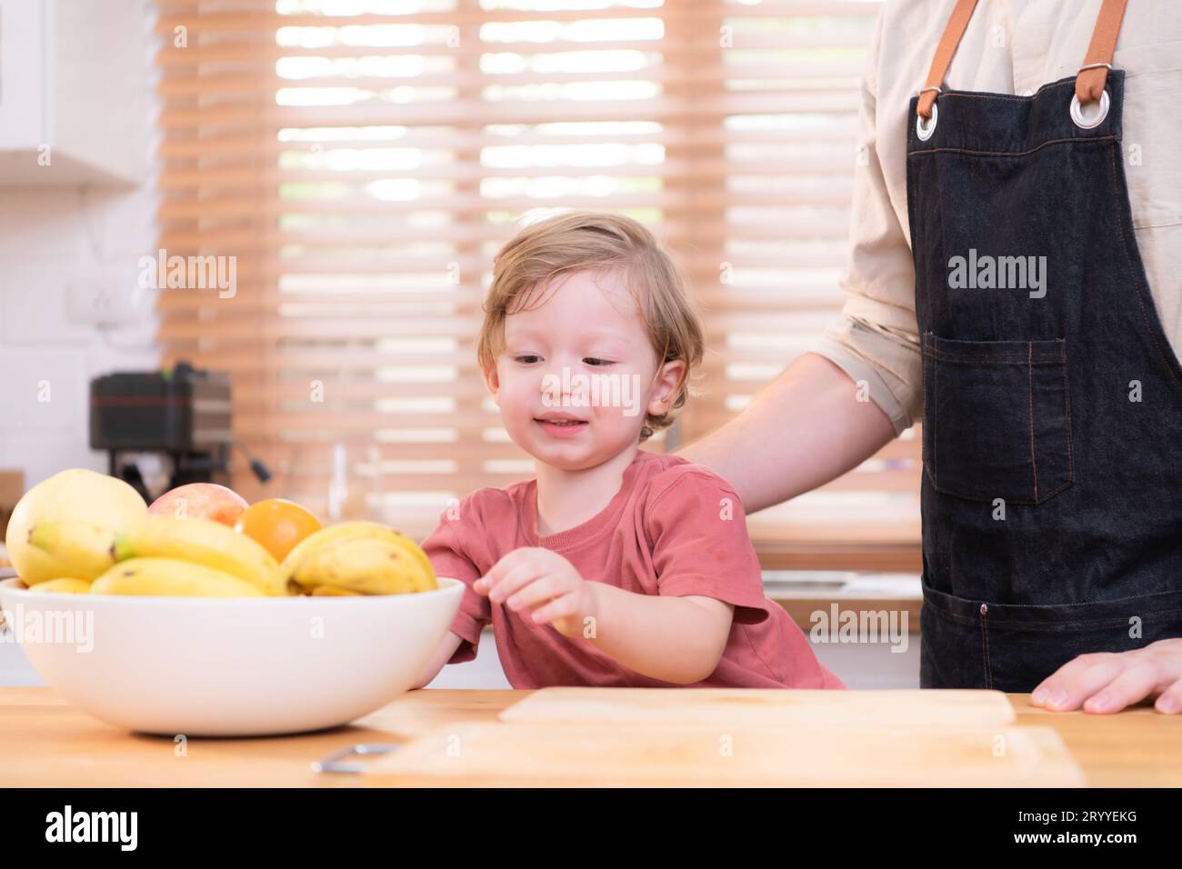 Mom and dad in the kitchen of the house with their small children. Have a good time making dinner together. Stock Photo